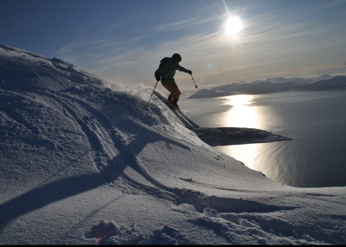 Mann på ski med sola i bakgrunnen