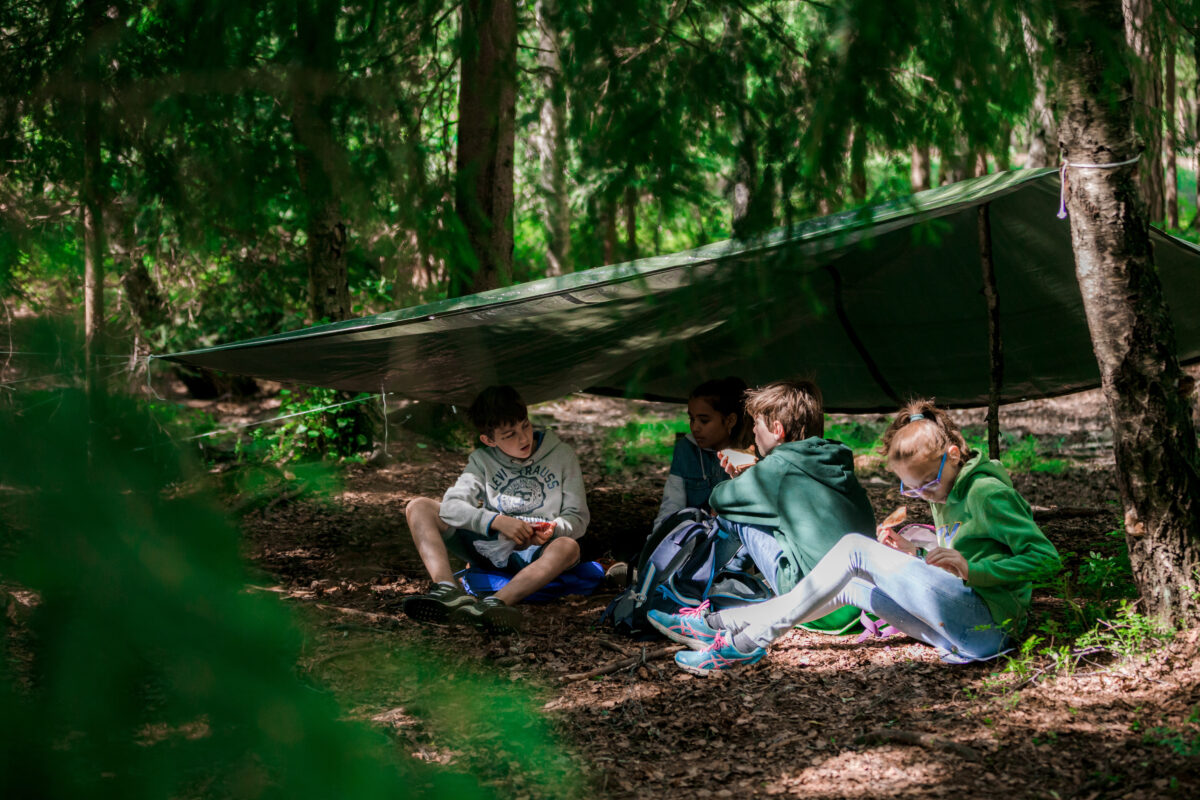 Skoleelever som sitter ute i en gapahuk i skolen.